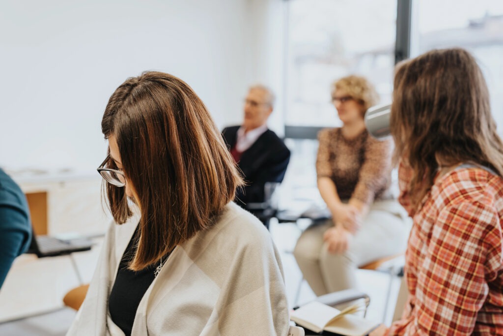 People gathered in conversation at a community event, seated together in a bright, welcoming space.